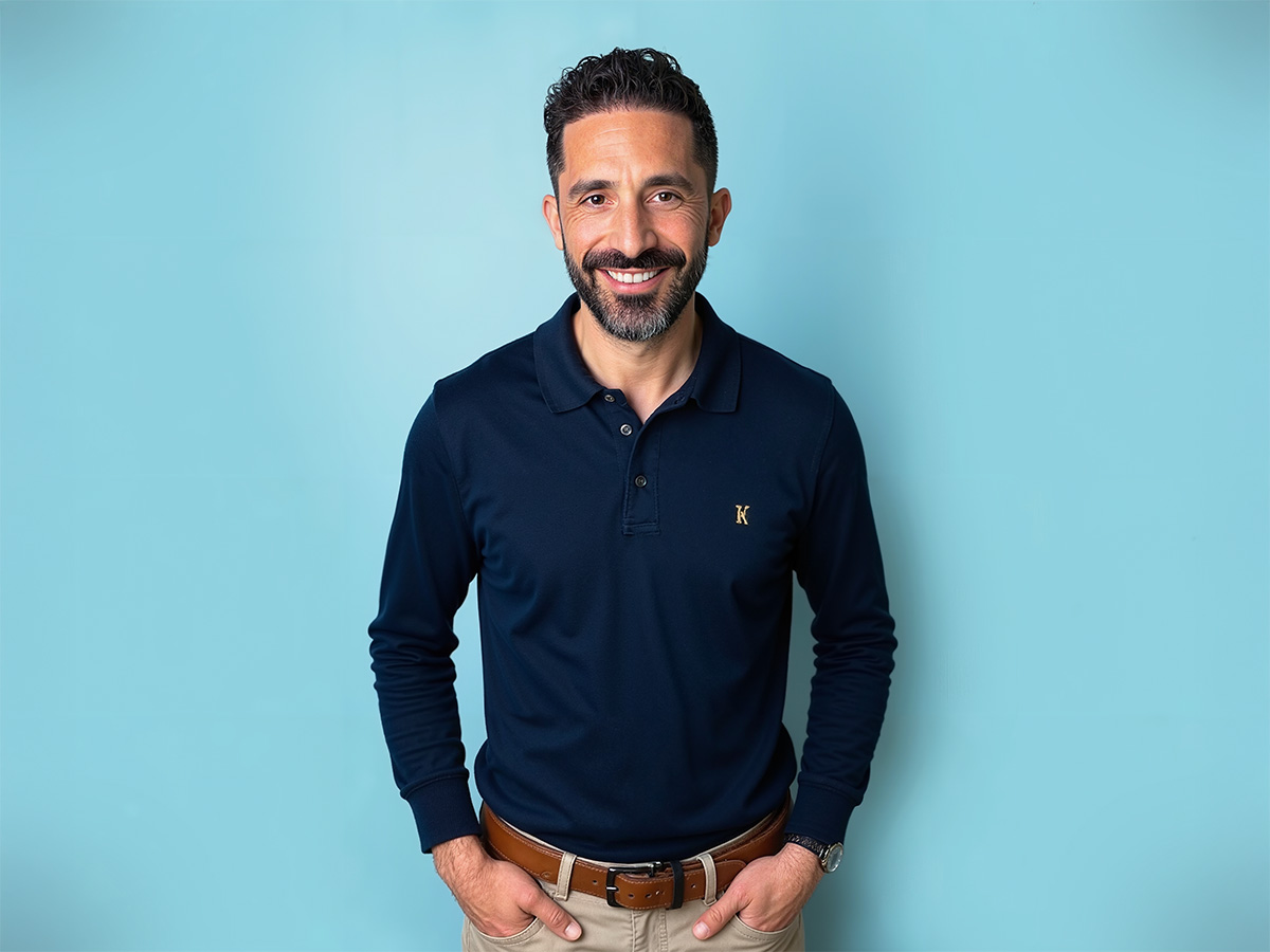 Upper body portrait of Nick Statman smiling with a blue background.